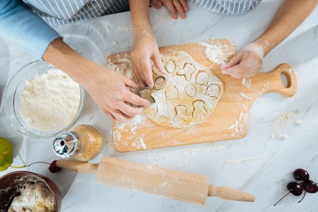 Funny molds. Sweet good little girl making some cookies and using funny molds while her mom helping...