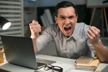 Emotional freedom. Stressful good looking male employee holding fists while crying and looking at the cameraの写真素材