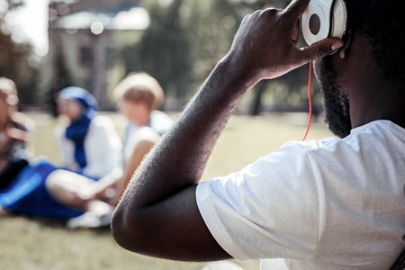 Electronic device. Positive nice young man holding his headphones and putting them on while listening to musicの写真素材
