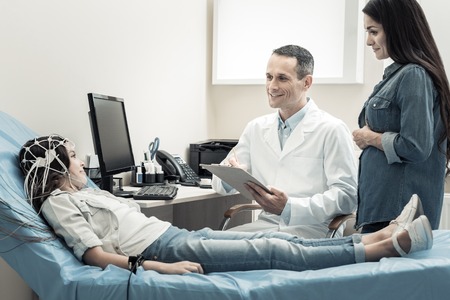 Do not worry. Happy nice male doctor smiling and looking at his young patient while preparing to start diagnosticsの写真素材