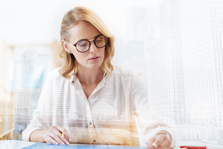 Busy day. Close up of talented young designer with glasses working at important task while expressing interest and concernの写真素材