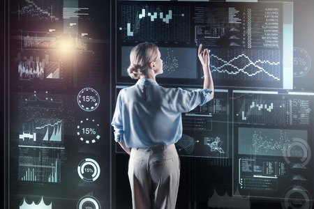 Attentive woman. Clever attentive experienced programmer standing in front of a big futuristic...