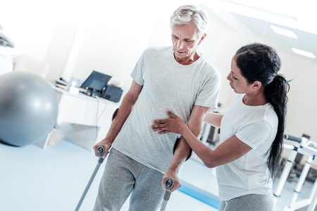 Attractive Concentrated Dark Haired Woman Helping A Serious Old