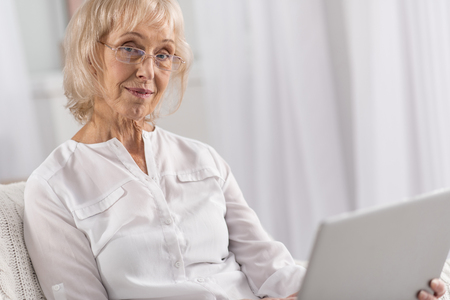 Pleasant tranquil mature woman wearing glasses while spending weekend and looking at cameraの写真素材