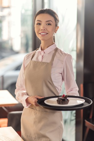 Professional service. Delighted nice professional waitress bringing food and smiling while working in the restaurantの写真素材