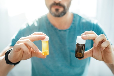 Helpful difference pills being in jars which man holding.の写真素材