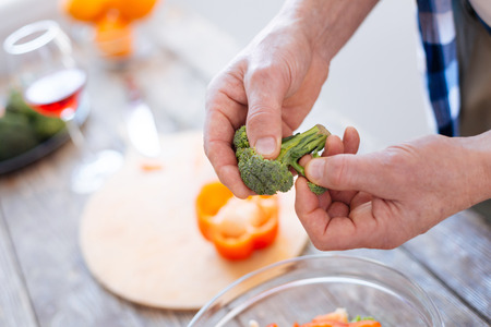 Selective focus of excellent juicy broccoli hooded and tore by male hands for preparing saladの写真素材
