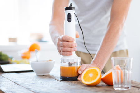 Close up of male hands holding orange fresh machine for drinking useful bright orangeの写真素材