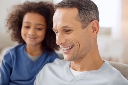 Good-looking content dark-haired smiling and his daughter sitting in the background and smilingの写真素材
