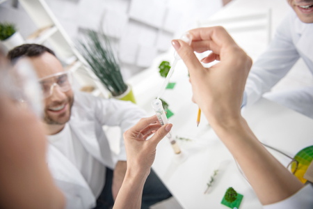 Waiting for results. Determined professional experienced scientists sitting at the table and wearing uniforms and doing some testsの写真素材