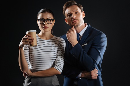Best colleagues. Interested thoughtful perspective partners standing in the dark room having a difficult task and looking straight.の写真素材