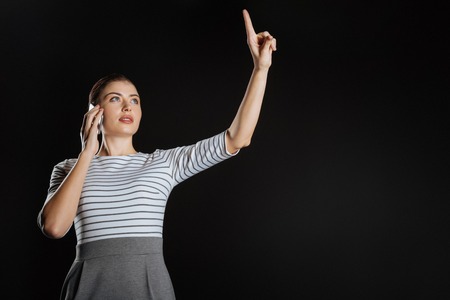 Business and creativity. Pretty occupied stylish woman being in the spacious room holding hand up...