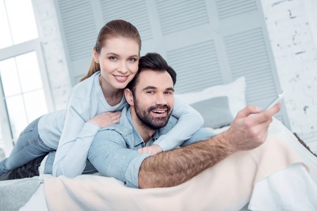 Love him. Joyful brunette keeping smile on his face and stretching right arm while looking at cameraの写真素材