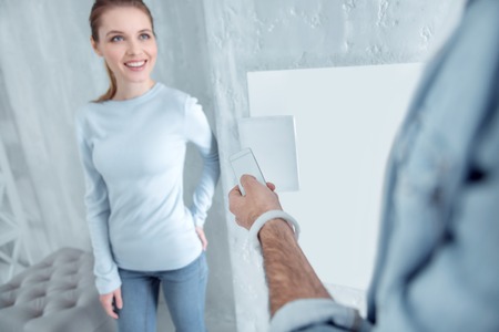 Positive emotions. Delighted female person keeping smile on her face and touching back while standing in front of her partnerの写真素材