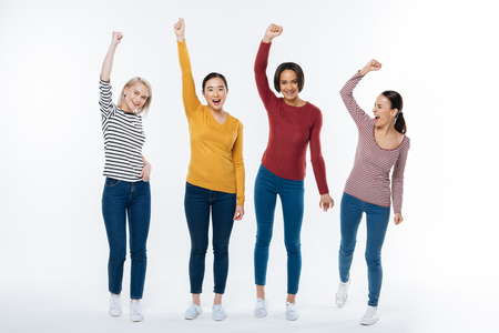 Our achievement. Joyful nice attractive women standing together and saying yes while being happy about their achievementの写真素材