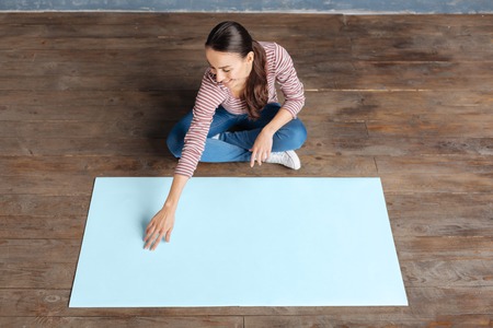 Female activist. Delighted nice positive woman sitting in front of the poster and smiling while looking at itの写真素材
