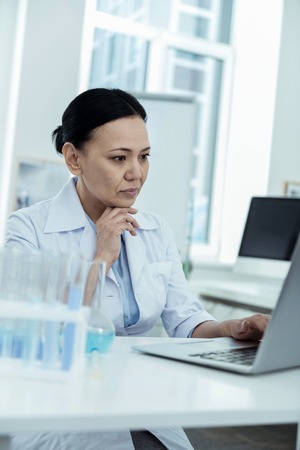 My project. Attractive concentrated dark-haired researcher wearing a uniform while working on her...