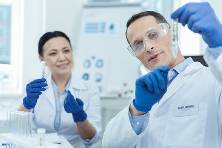 Lab research. Professional researchers holding test tubes while workign in a labの写真素材