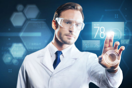 Careful specialist. Attentive progressive qualified doctor thoughtfully touching the screen of a...