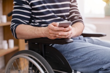 Typing message. Paralyzed man sitting on wheelchair and communicating onlineの写真素材