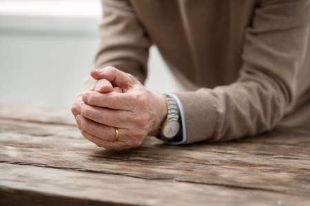 Now I am lonely. Hands of a cheerless aged man being put on the table while suffering from lonelinessの写真素材