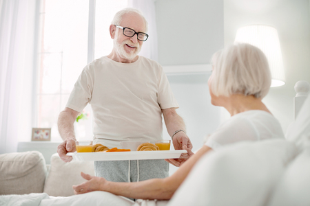Family relations. Joyful positive senior man looking at his wife while showing his careの写真素材