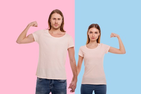 Stronger together. Pleasant young couple holding hands, intertwining their fingers, while raising...