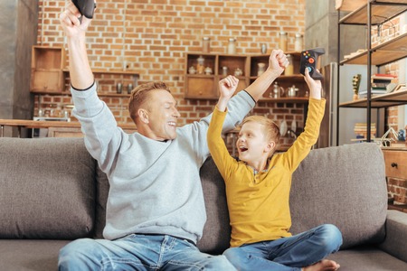 Our victory. Joyful nice emotional father and son looking at each other and holding their hands up...