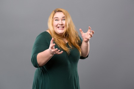 Happy nice woman standing against grey background while showing her emotionsの写真素材