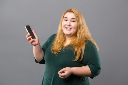 Joyful obese woman holding her phone while making a callの写真素材