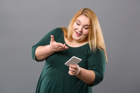 Joyful positive woman looking at the smartphone screen while receiving a new messageの写真素材