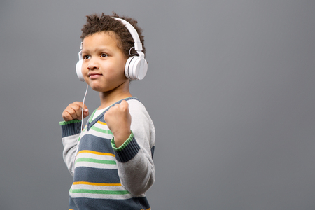 Leisure time. Joyful positive boy wearing headphones while listening to musicの写真素材
