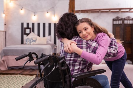 Work on relationships. Merry girl hugging disabled woman who turning with her backの写真素材