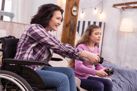 Genuine fun. Merry incapacitated woman and girl using controller while playing game