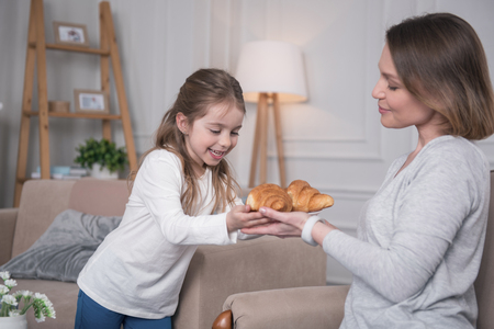My dessert. Loving alert mother holding cookies and giving them to her daughterの写真素材