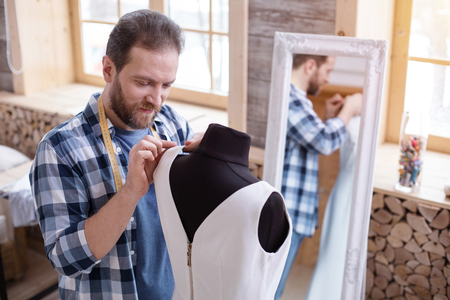 My idea. Concentrated male designer touching dress while looking downの写真素材