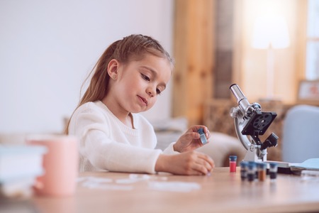 Curious child. Positive curious girl looking at the bottles while being curious what is inside themの写真素材