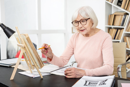 Useful task. Energetic senior woman studying while pointing at bookの写真素材