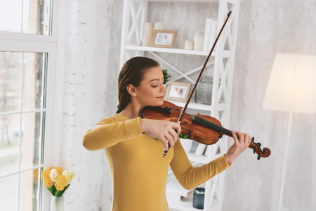Pretty girl expressing positivity while playing the violinの写真素材