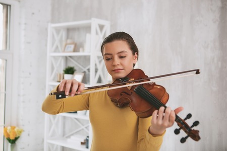 Cheerful musician looking downwards while playing the violinの写真素材