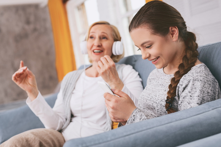 Cheerful brunette female keeping smile on her face while choosing melodyの写真素材