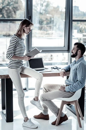 I will help you. Friendly young reliable colleagues sitting in the office looking at each other and working.の写真素材