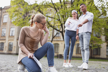 Rude students. Two rude students bulling blonde-haired pleasant girl while walking around the student campusの写真素材