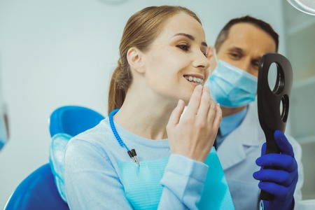 Having consultation. Cheerful female keeping mouth opened while examining her teeth