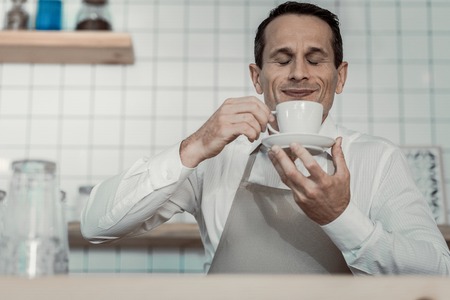 Be happy. Attractive waiter keeping smile on face while beginning working day with pleasureの写真素材