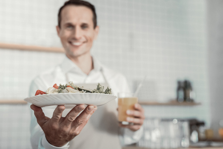 Refresh yourself. Pleased waiter smiling while serving dish to his clientの写真素材