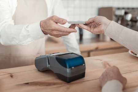Paying the check. Focused photo on electronic device that lying on the table and being ready for...