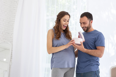 Great surprise. Amazed pregnant woman opening gift and shoutingの写真素材