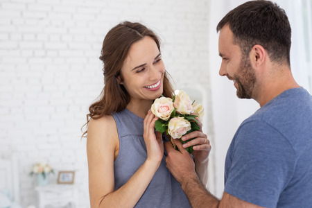 Best wife. Adorable man presenting flowers to pregnant woman who smilingの写真素材