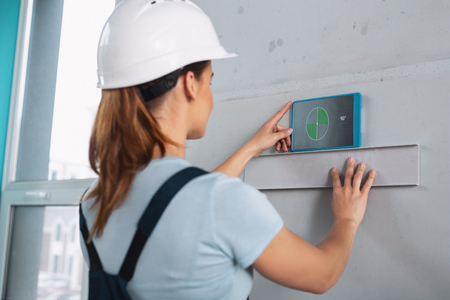 Female professional builder wearing a uniform and working with her instruments
